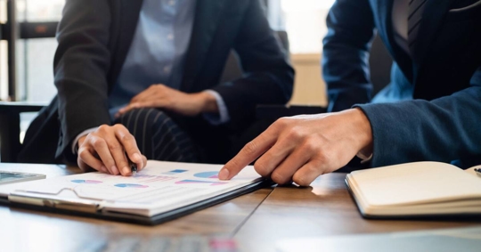 two people while pointing at the paper
