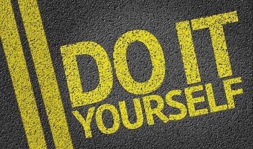 Shot looking down at a road with solid double-yellow lines with "DO IT YOURSELF" spray painted in yellow on the road